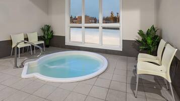 Ein Poolbereich mit Whirlpool, Stühlen und Topfpflanzen.