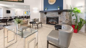 A modern lounge area with a stone fireplace, leather seating, and a glass coffee table.