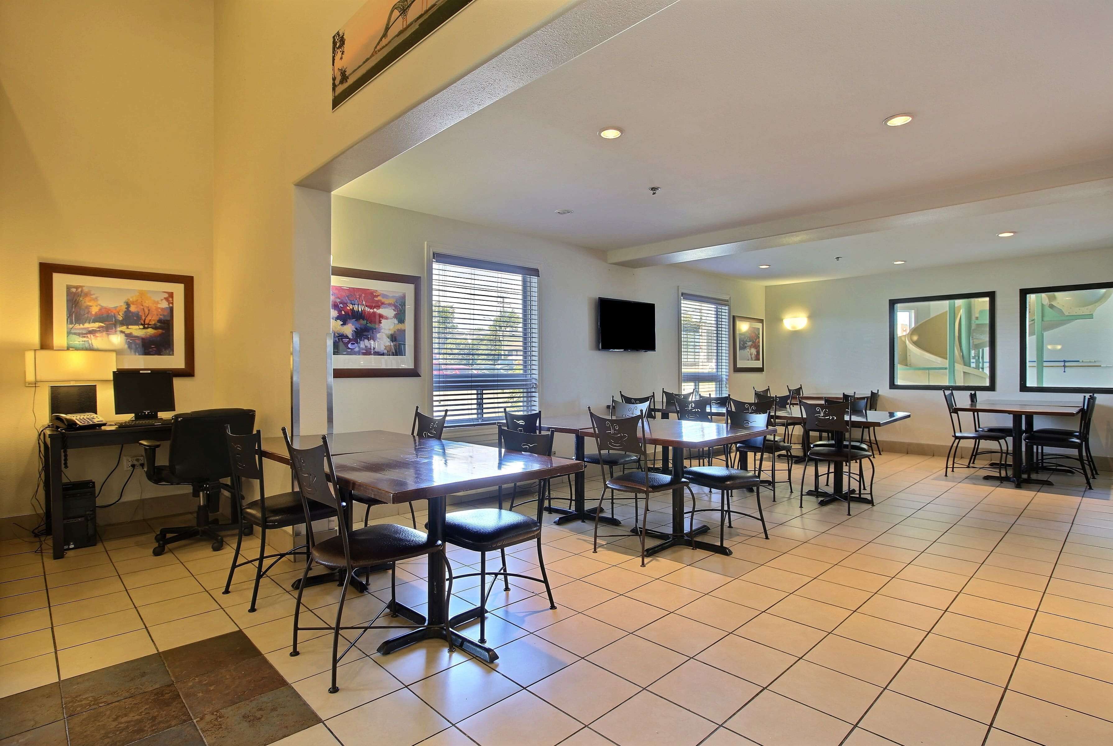 A spacious meeting room with multiple tables and chairs, a computer setup, and artwork on the walls.