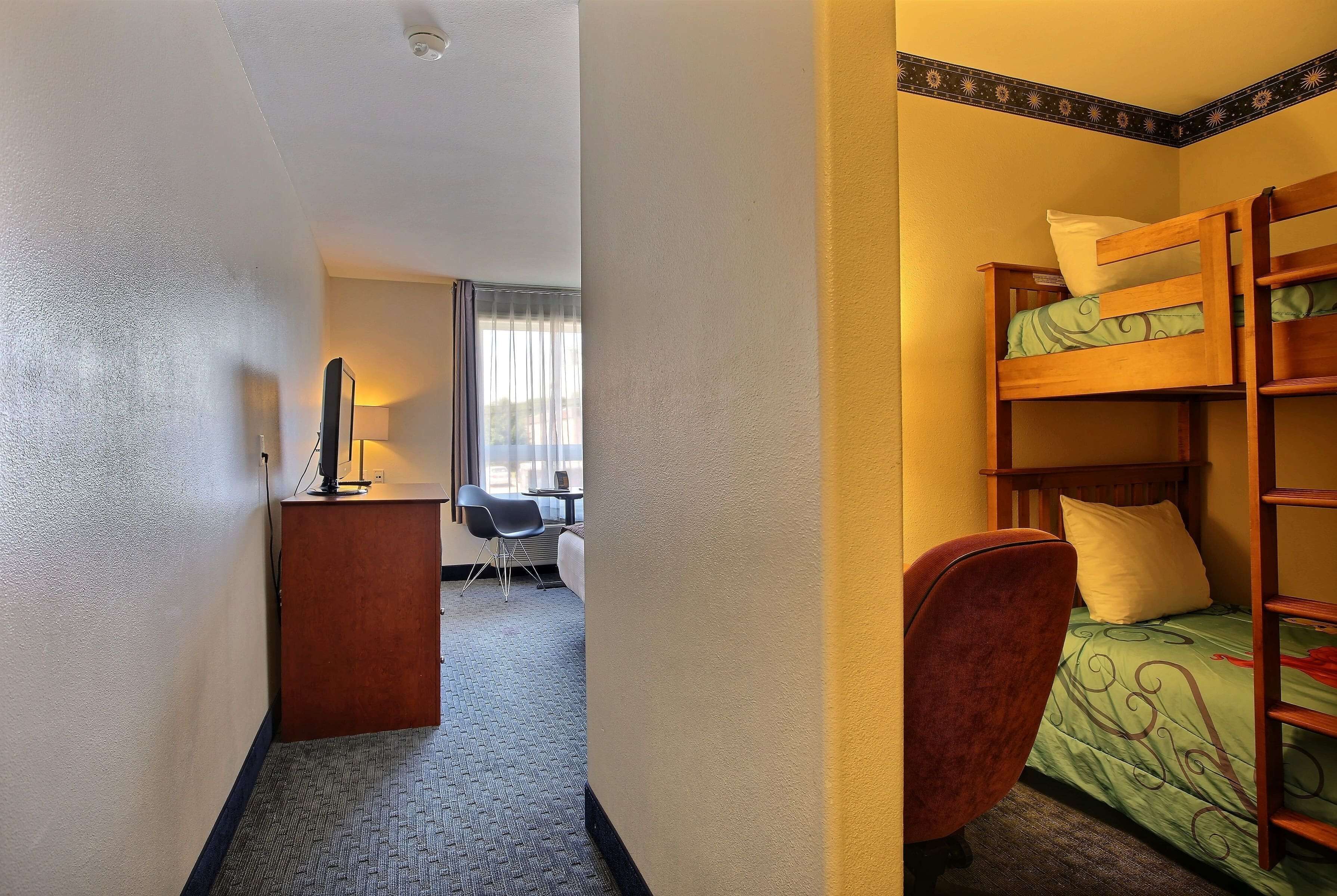 Una habitación de hotel con literas, un escritorio con lámpara y una silla.
