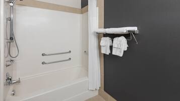 A bathroom with a bathtub, shower, and towel rack with towels.