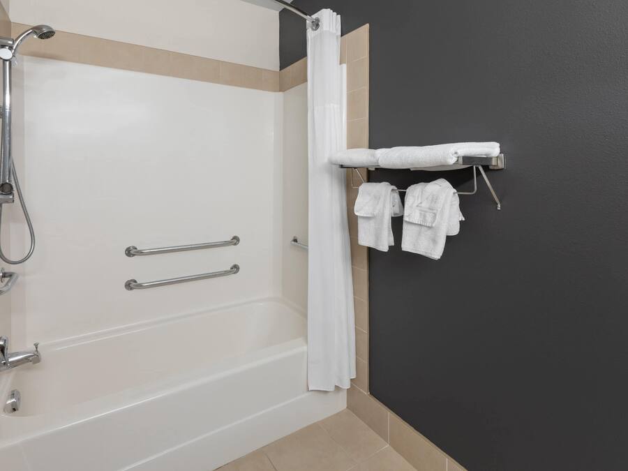 A bathroom with a bathtub, shower, and towel rack with towels.