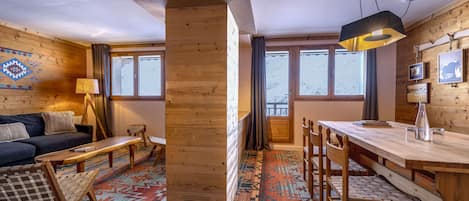 Une pièce chaleureuse avec un décor intérieur en bois, un canapé, une table à manger avec des bancs et un tapis à motifs.