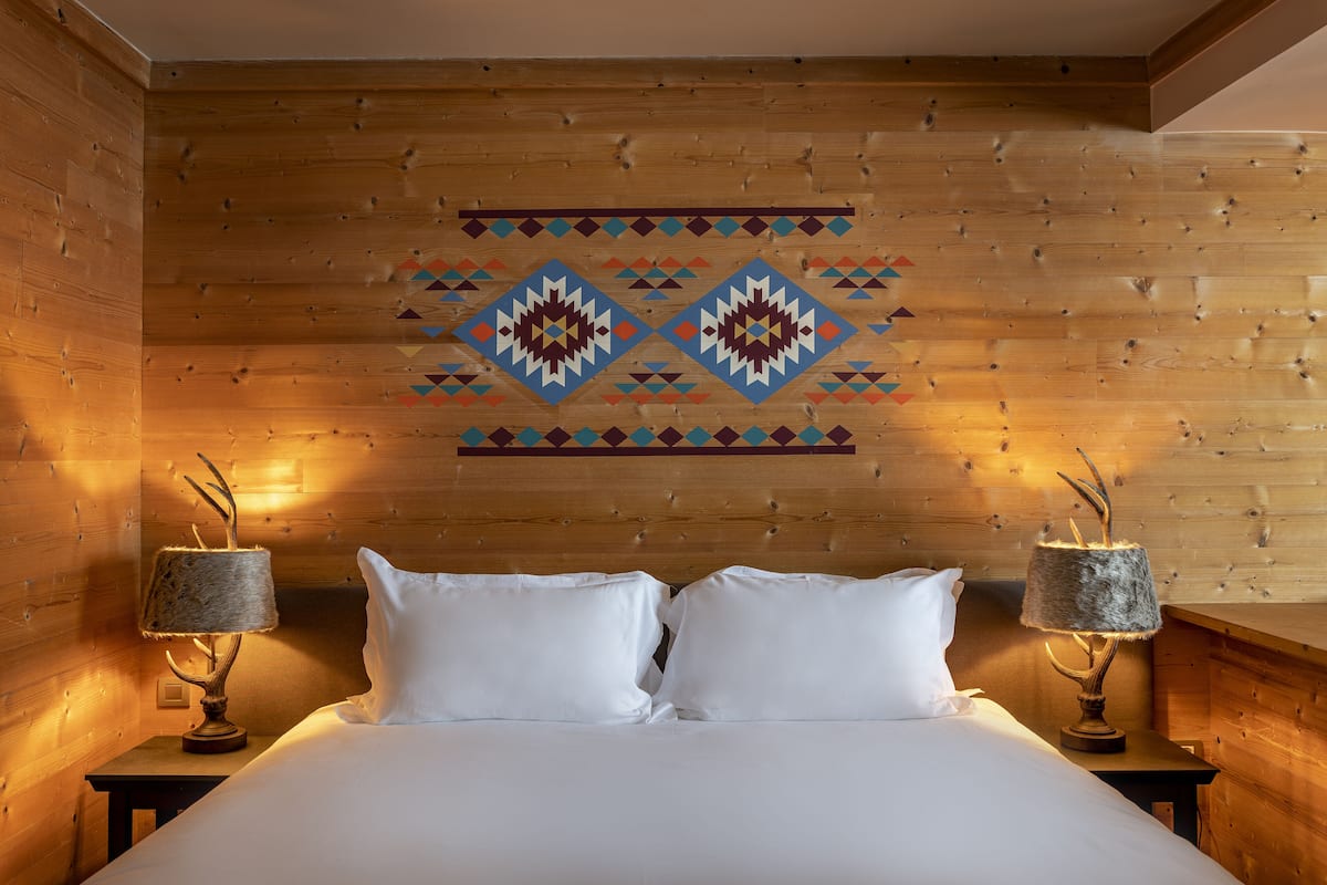 A wooden-paneled room with a bed, two nightstands, and a decorative wall pattern.