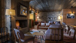 Ein gemütlicher Loungebereich mit Steinwand, Holzbalkendecke und bequemen Sitzmöglichkeiten.