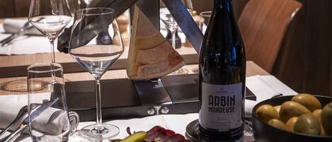 A table set with a bottle of wine, glasses, a knife, a plate of meat, and a bowl of potatoes.