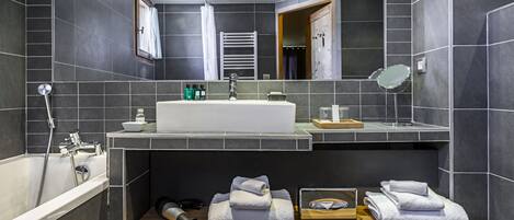 A modern bathroom with a large sink, mirror, and towel rack.