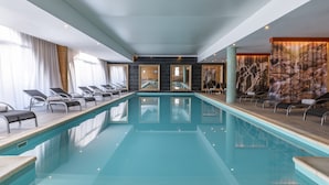 Ein moderner, überdachter Pool mit klarem Wasser, Liegestühlen und Blick ins Innere.