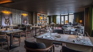 Ein Restaurant mit mehreren Tischen, Stühlen und einem Bücherregal.