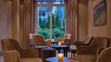 A room with four armchairs, a round table, and a lit candle.