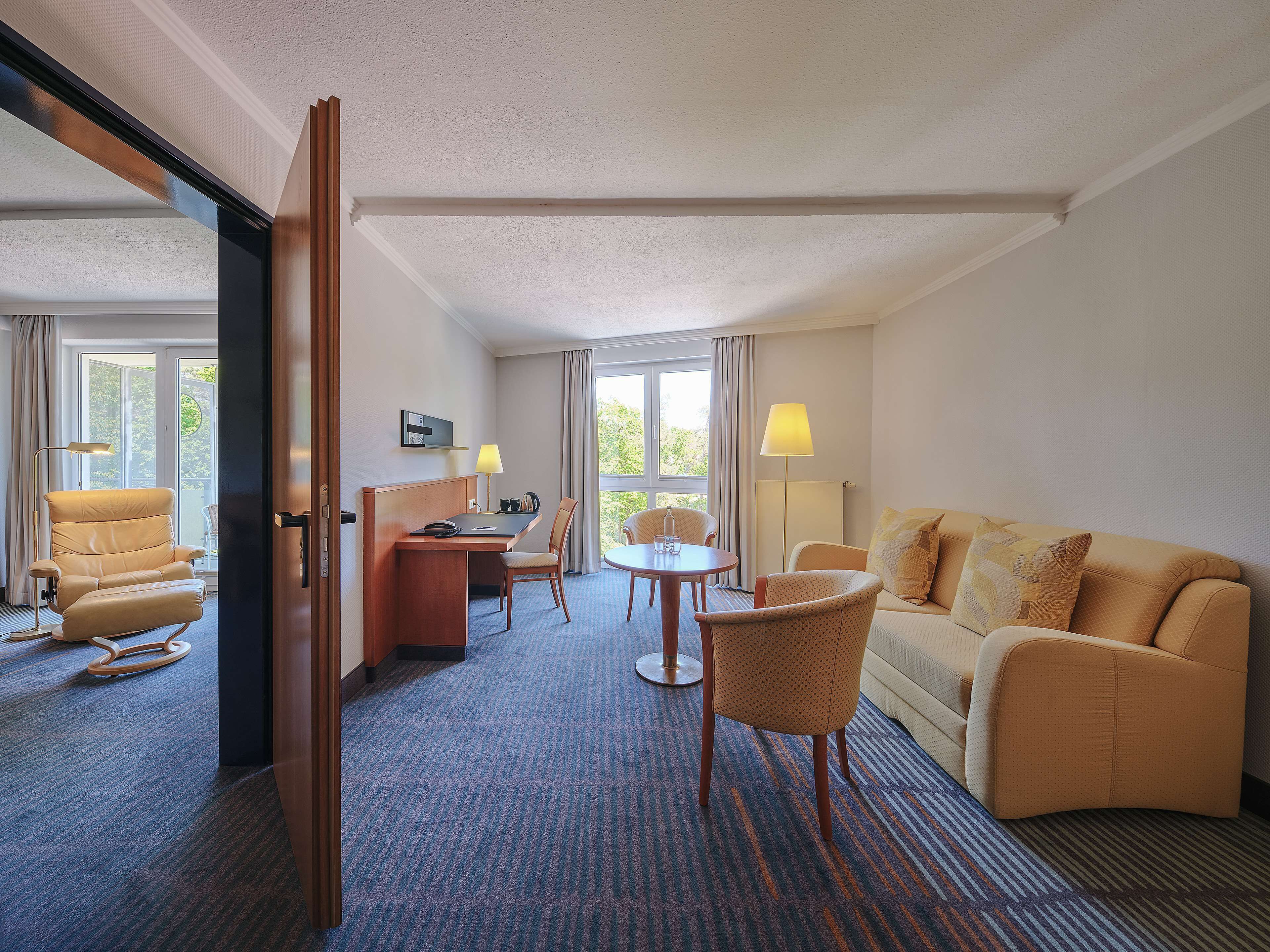 Una habitación de hotel con sofá, sillón, escritorio y sillas.