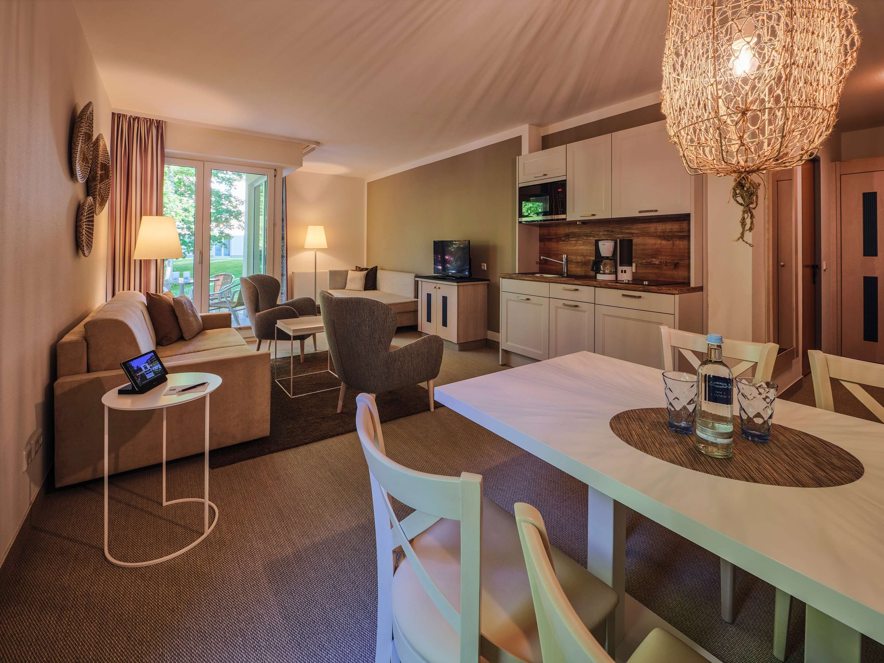 Une chambre d’hôtel moderne dotée d’un espace salon, d’une kitchenette et d’un coin repas.