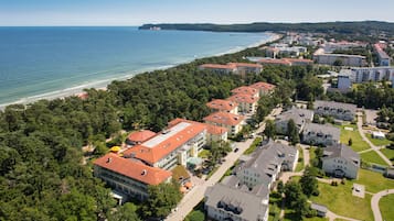 Stunning coastal hotel area with red-tiled roofs and lush greenery, featuring a central courtyard and beach views.