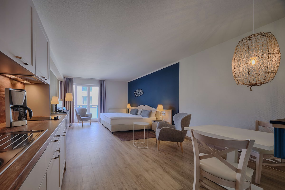 Une chambre d’hôtel moderne équipée d’une kitchenette, d’un lit, d’un canapé et d’un coin repas.