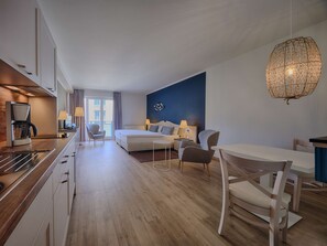 A modern hotel room with a kitchenette, a bed, a sofa, and a dining area. - Dorint Seehotel Binz-Therme Binz/Rügen (Binz)