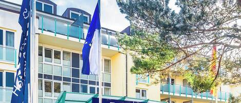 Entrada de un hotel con fachada de vidrio, un letrero que dice 'Dorne Hotels & Resorts' y dos banderas.