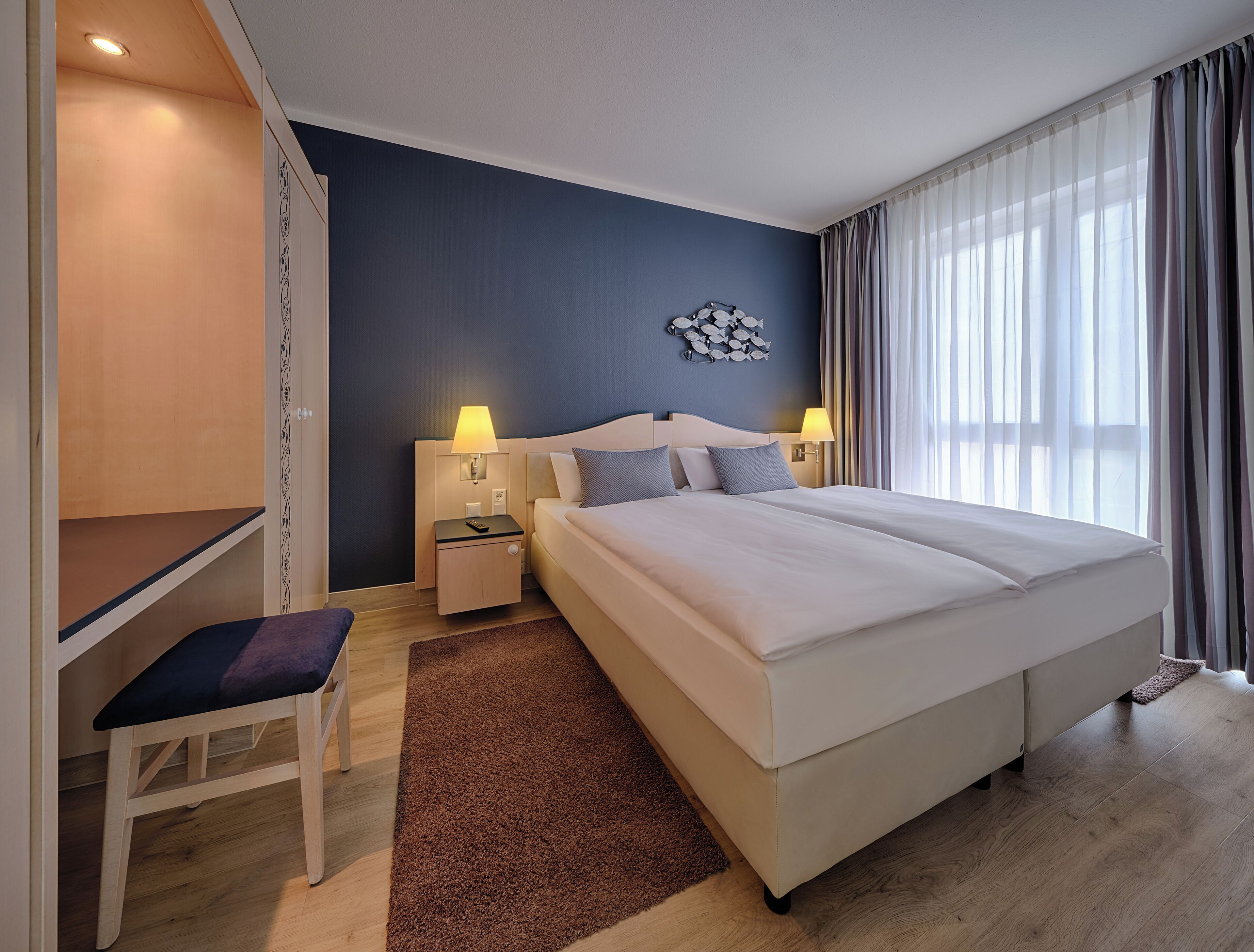 Una habitación de hotel moderna con una cama grande, un escritorio y una silla.