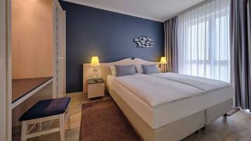 Una habitación de hotel moderna con una cama grande, un escritorio y una silla.