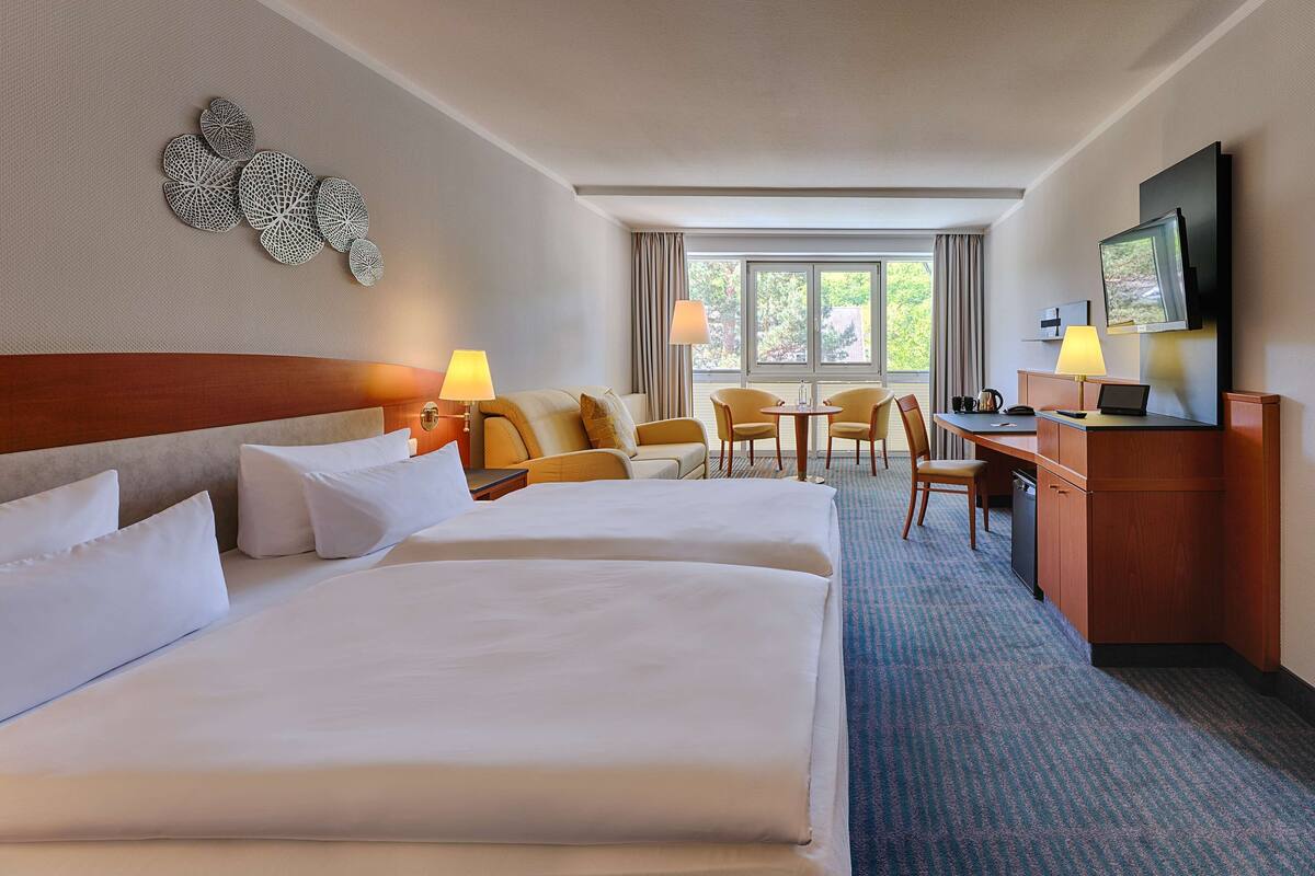Une chambre d’hôtel avec deux lits, un bureau, une chaise et un téléviseur.