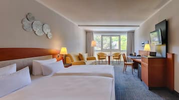 A hotel room with two beds, a desk, a chair, and a TV.
