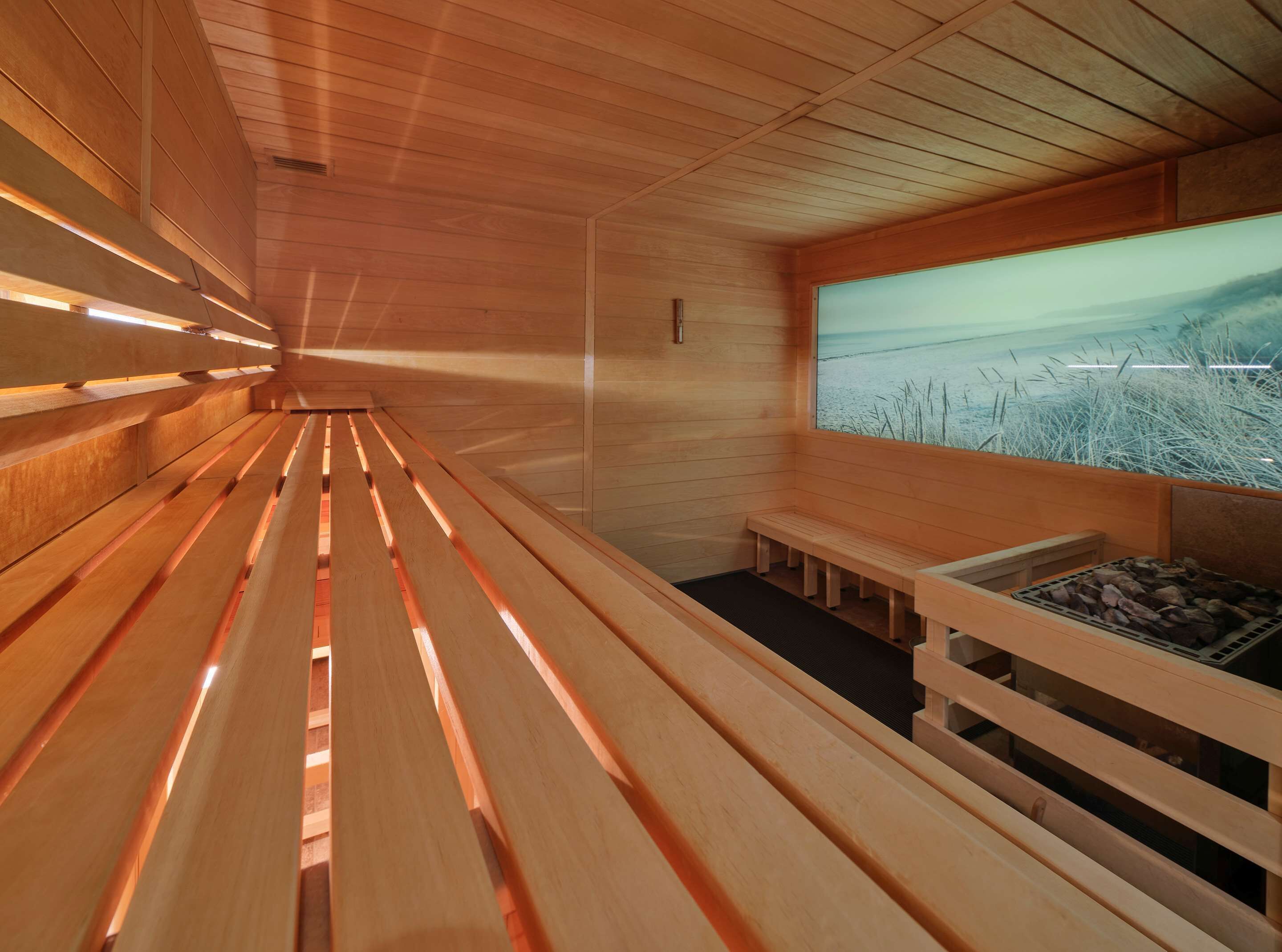 Una sauna con bancos de madera y un amplio ventanal con vistas al paisaje.