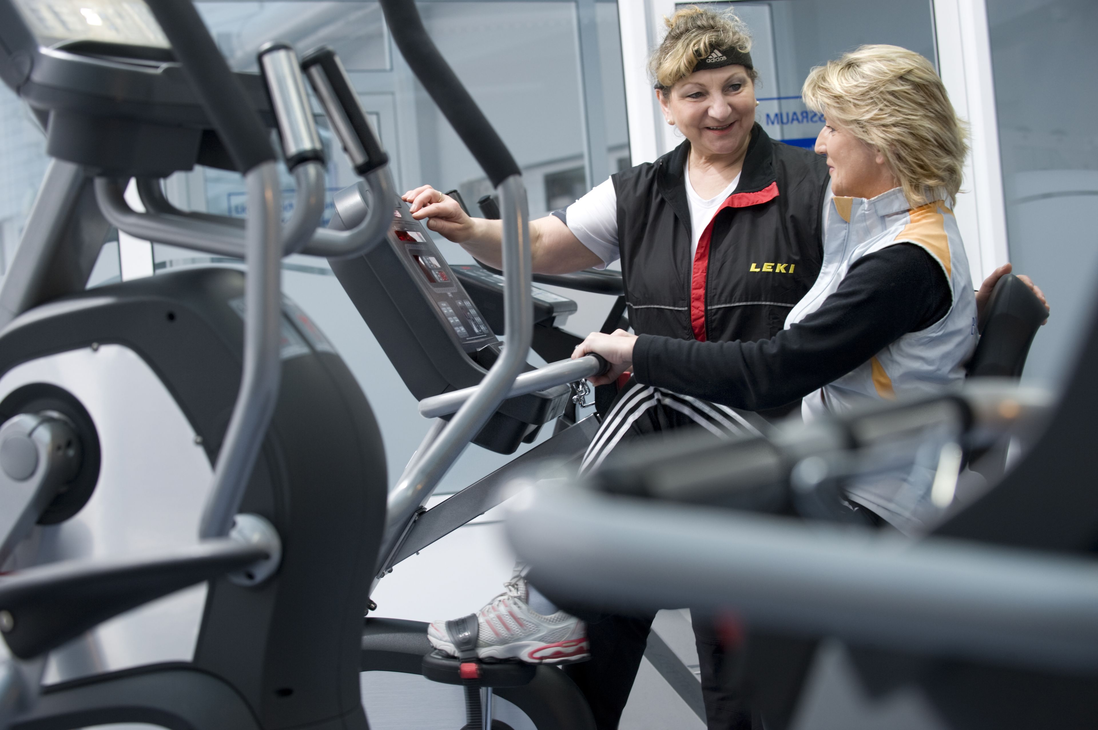 A gym with exercise equipment and two people interacting.