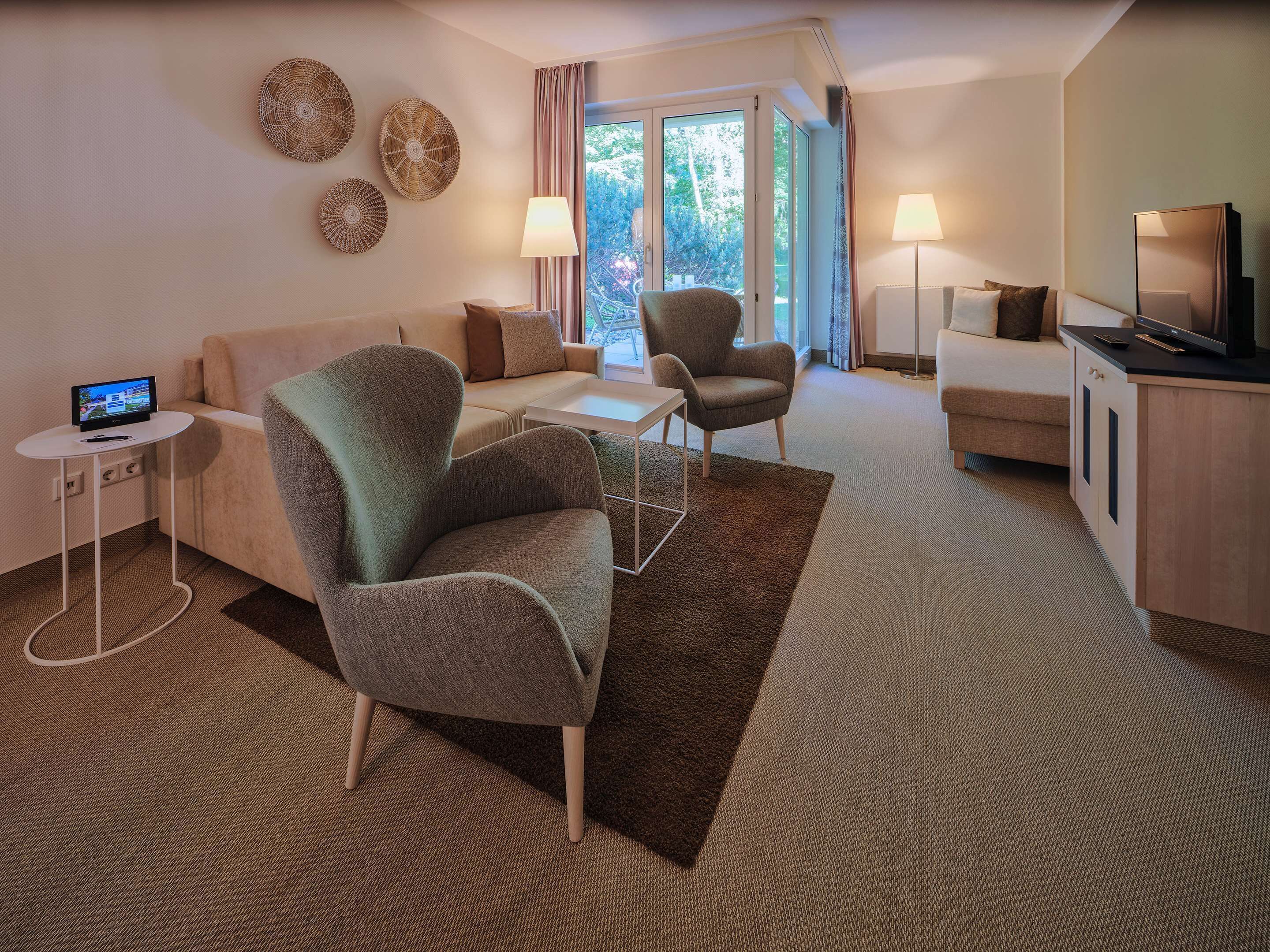 A modern living room with a sofa, armchair, and a TV on a stand.