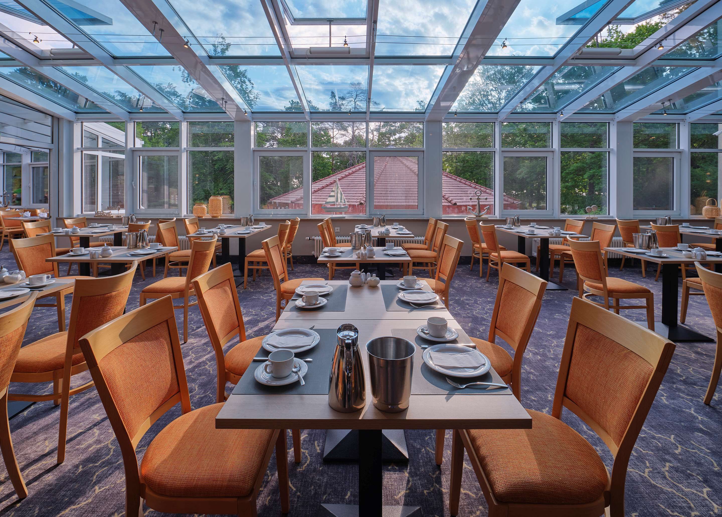 Un comedor espacioso con mesas y sillas, ventanas amplias y vistas al exterior.