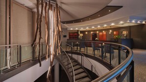 A modern hotel lobby with a curved staircase, a reception desk, and a seating area. - Dorint Seehotel Binz-Therme Binz/Rügen (Binz)
