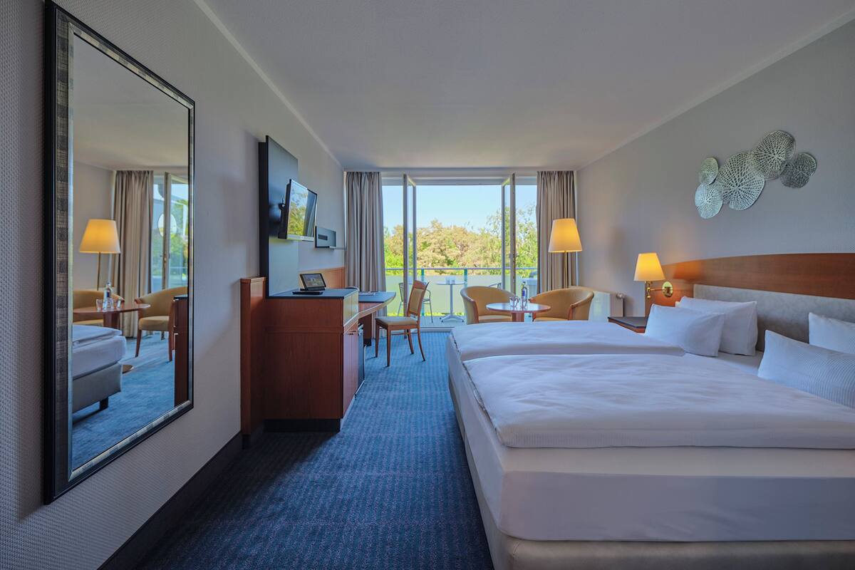 Une chambre d’hôtel avec un grand lit, un bureau, une chaise, une télévision et un balcon avec vue.