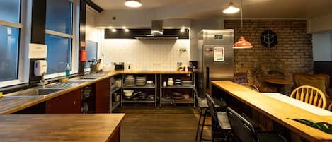 A modern kitchen with a wooden counter, bar stools, and a brick accent wall.