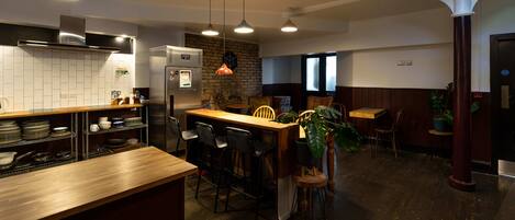 A modern kitchen with a wooden counter, bar stools, and a dining area with a table and chairs.