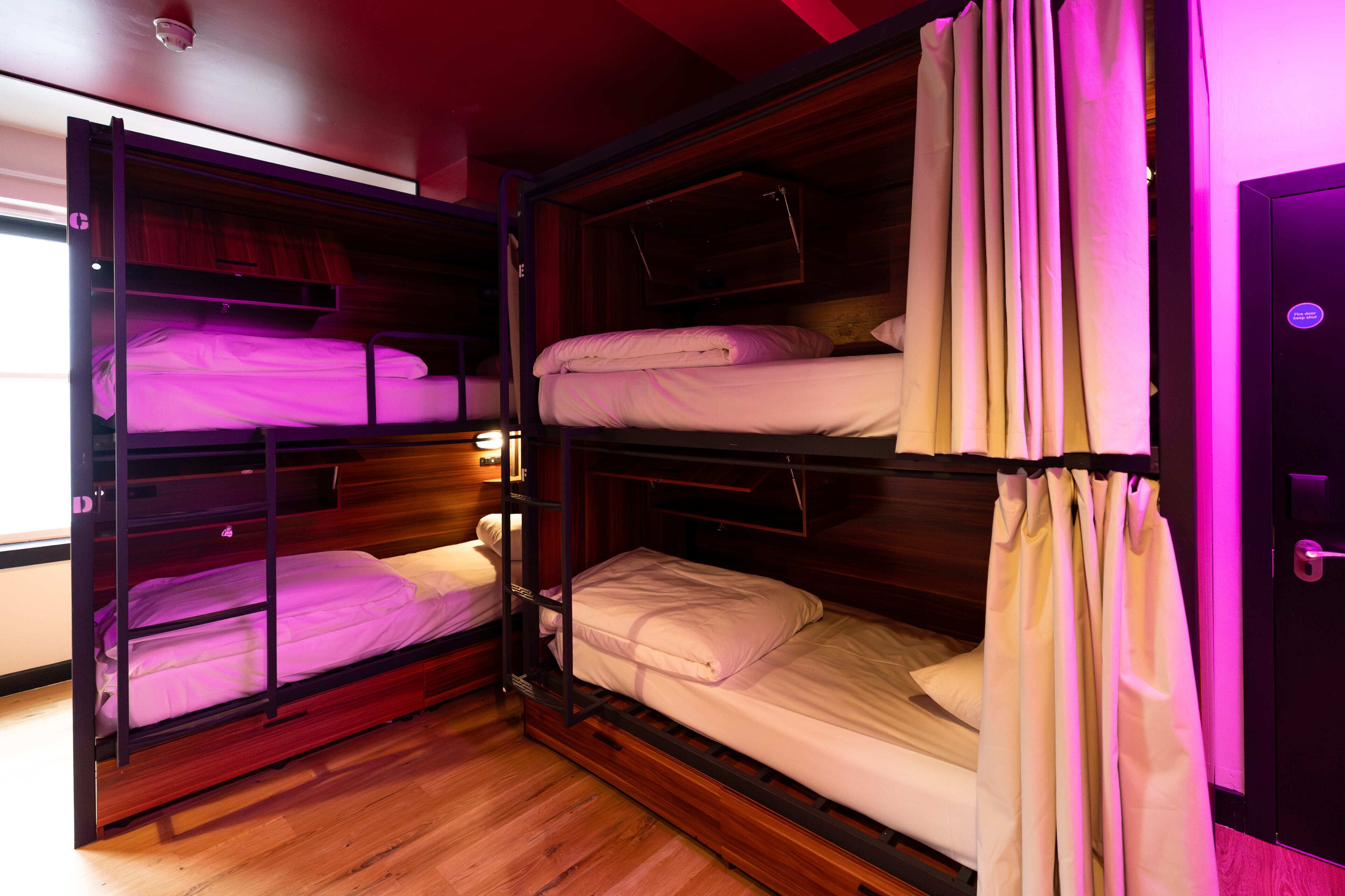 Una habitación con literas, suelo de madera y una puerta con manija.