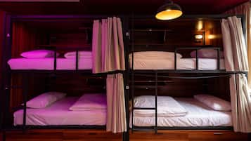 Habitación con literas, suelo de madera, lámpara colgante y un pequeño reloj de pared.