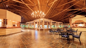 A spacious lobby with a high wooden ceiling, a central seating area with chairs, and a reception desk. - Catalonia Playa Maroma – All Inclusive (Playa del Carmen)