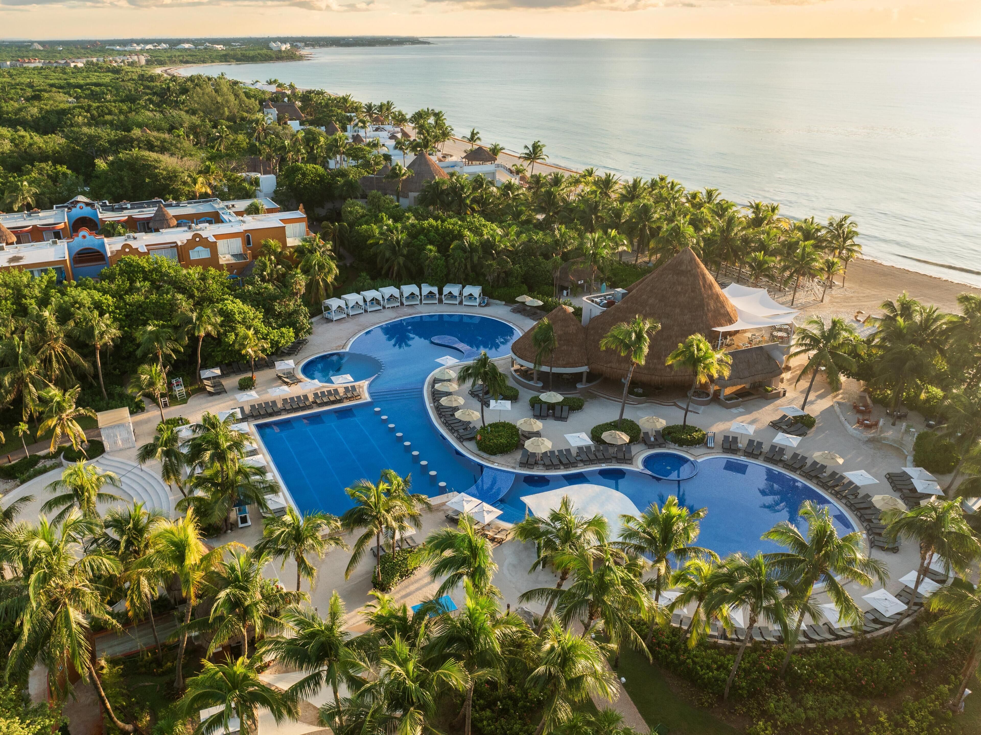 A resort with a large central pool, multiple smaller pools, and a beach area.