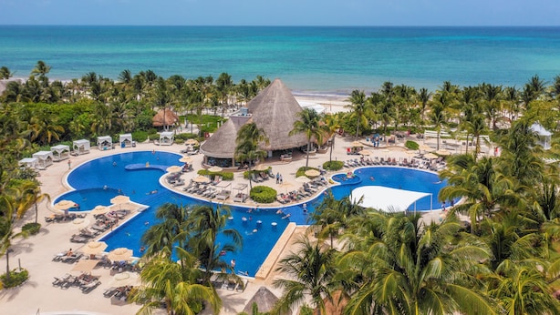 A resort with a large central pool, palm trees, and a beach. - Catalonia Playa Maroma – All Inclusive (Playa del Carmen)