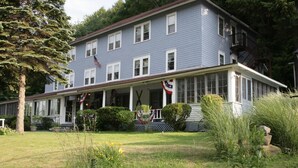 A two-story house with a covered porch and a flag. - The Inn at Starlight Lake (Starlight)