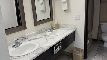 A bathroom with two sinks, a mirror, and a towel rack.