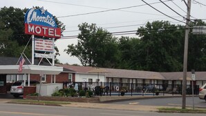 A motel with a large sign, a fenced parking area, and a pool. - Moonlite Motel Niagara Falls (Niagara Falls)