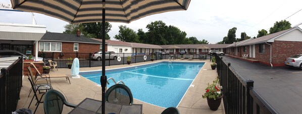 A swimming pool with a fenced deck, outdoor seating, and a covered patio area. - Moonlite Motel Niagara Falls (Niagara Falls)