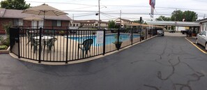 A fenced pool area with tables and chairs, a gas station in the background, and a building with a 'Cove' sign. - Moonlite Motel Niagara Falls (Niagara Falls)