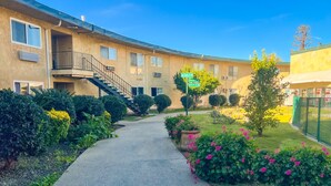 A building with a central staircase leading to a balcony, surrounded by well-maintained gardens and a clear sky. - Hometown Inns North Hills (North Hills)