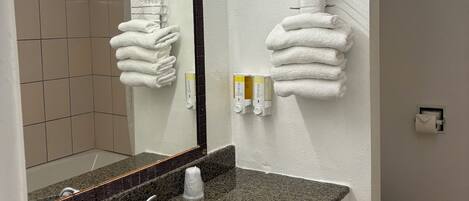 Un baño con lavamanos de encimera de granito, un espejo, toallero y un inodoro.