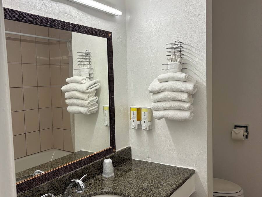 Un baño con lavamanos de encimera de granito, un espejo, toallero y un inodoro.
