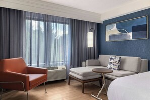 A hotel room with a sofa, a chair, a small table, and a large window with curtains. - Courtyard by Marriott Pittsburgh Monroeville (Monroeville)