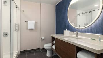 Une salle de bain moderne avec une douche à parois de verre, des toilettes, un lavabo avec un miroir et un porte-serviettes.