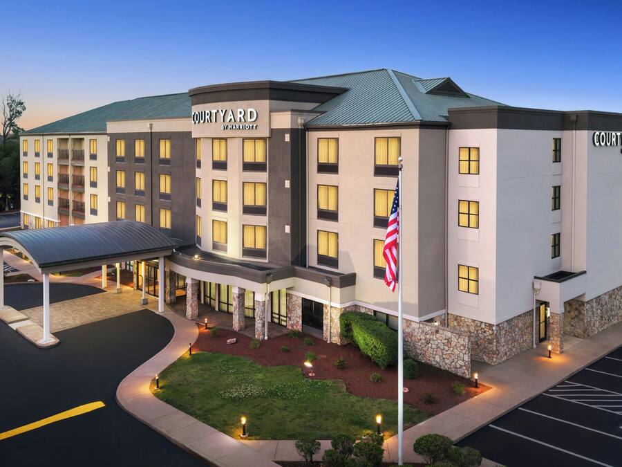 A multi-story hotel with a flat roof, a covered entrance, and a parking lot.