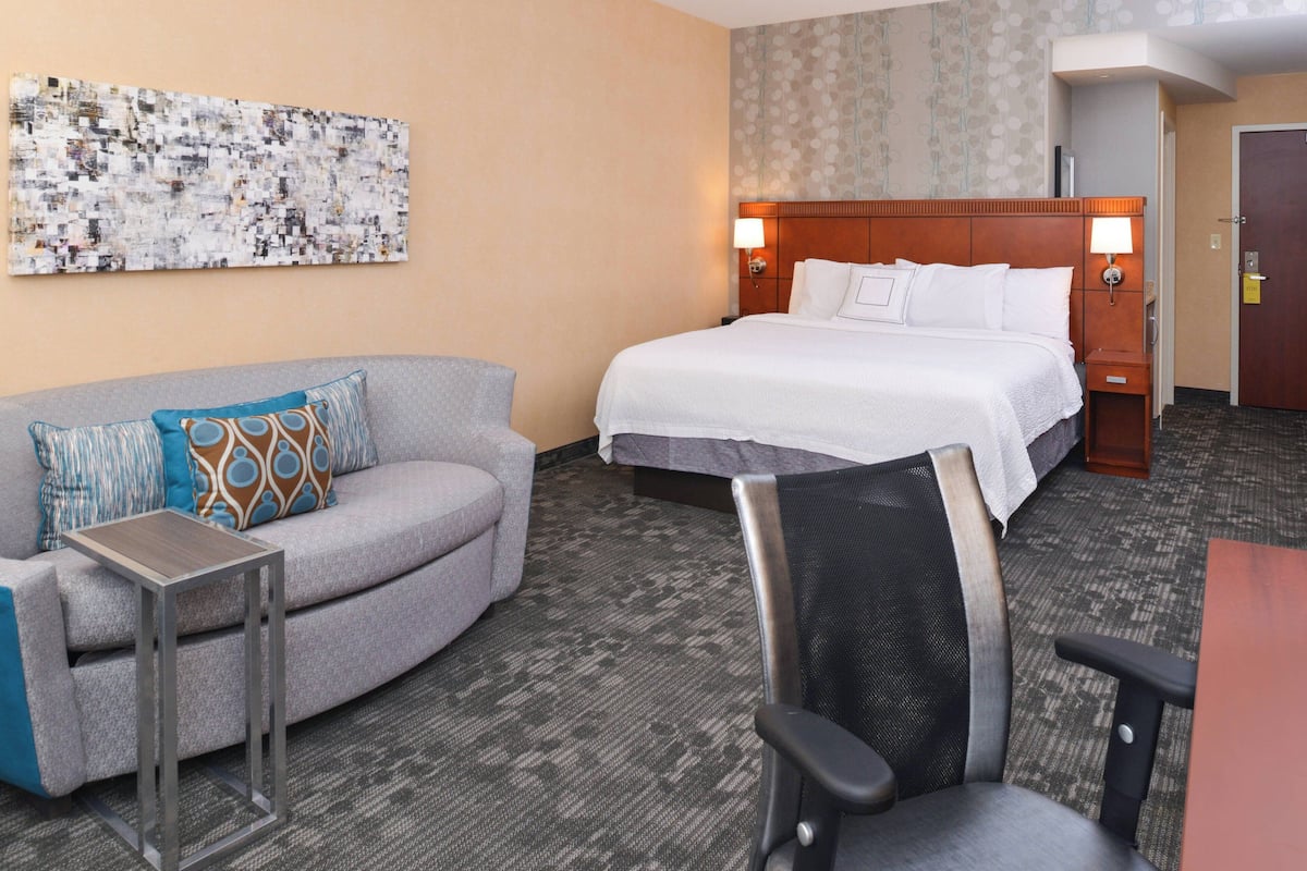 A hotel room with a bed, a sofa, a small table, and a chair.
