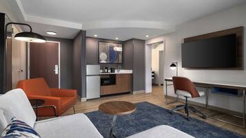 Une chambre d’hôtel moderne équipée d’un canapé, d’un coin repas, d’une cuisine et d’une télévision.